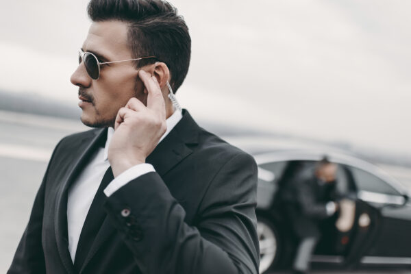 handsome bodyguard of businessman listening message with security earpiece