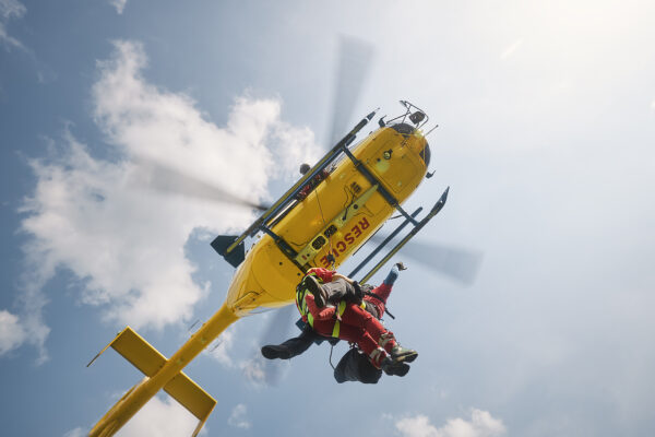Two paramedics hanging on rope under flying helicopter emergency medical service. Themes rescue, help and heroes.