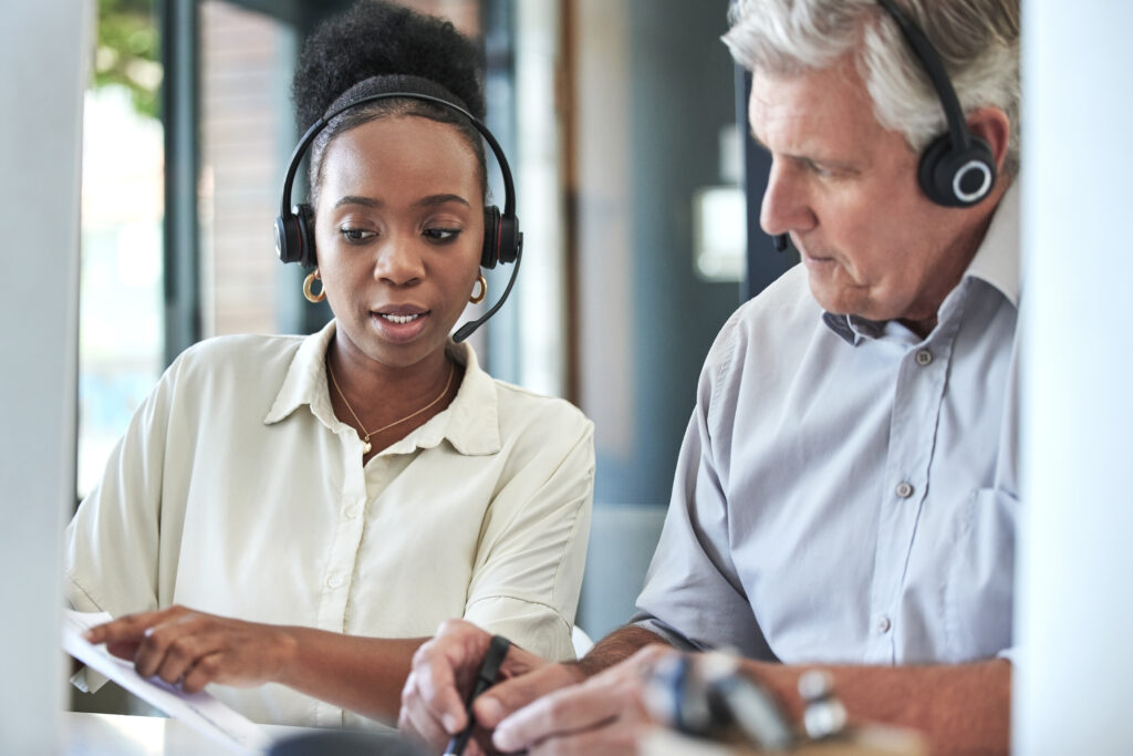 Two business people working with computers and wearing headsets.