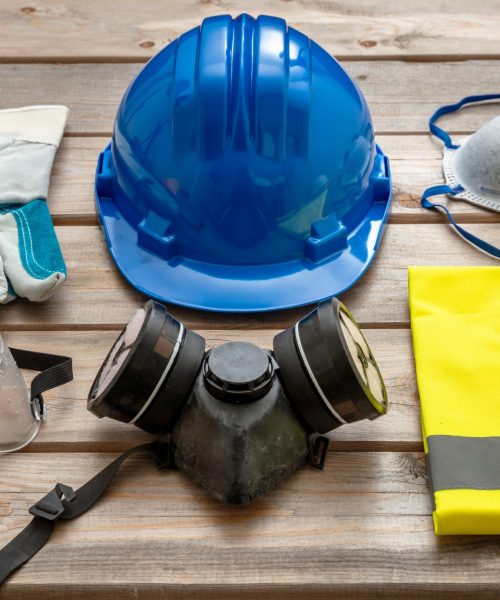 Work safety protection equipment. Industrial protective gear on wooden background. Construction site health and safety concept