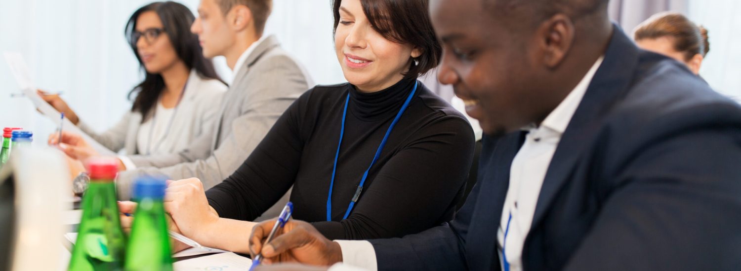 business, people and education concept - businessman and businesswoman at conference discussing papers