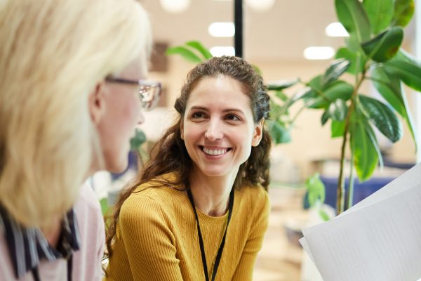 Two contemporary businesswomen in smart casual sitting in office and discussing financial questions