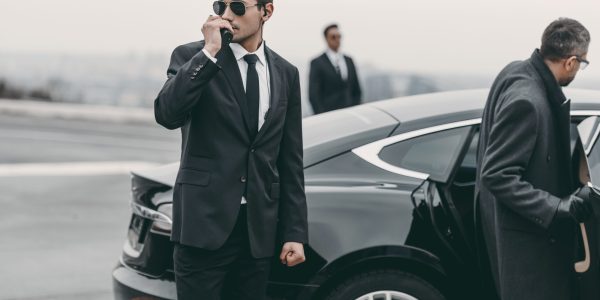 Car driver updating corporate travel management company about the schedule as the passenger enters the car.