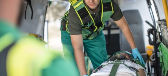 A patient being moved into an ambulance by a medical team to be transferred to a different location.