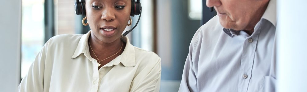 Two business people working with computers and wearing headsets.